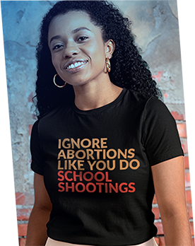 A woman wearing a t-shirt that says, “IGNORE ABORTIONS LIKE YOU DO SCHOOL SHOOTINGS” in orange with “SCHOOL SHOOTINGS" in red. 
