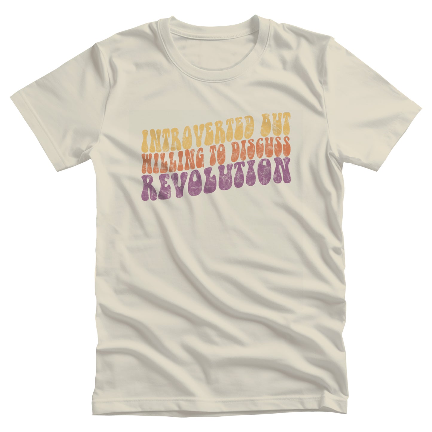 Natural color unisex t-shirt with a vintage graphic on it that looks worn and grungy. The graphic says “Introverted but willing to discuss revolution” in a retro font in all caps. Each line is a different color: “Introverted but” is a retro yellow, “willing to discuss” is a retro red, and “Revolution” is a retro purple. The graphic is a wavy shape and slopes upwards to the right.