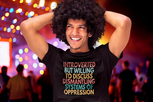 A man of color wearing a t-shirt that says "Introverted but willing to discuss dismantling systems of oppression."