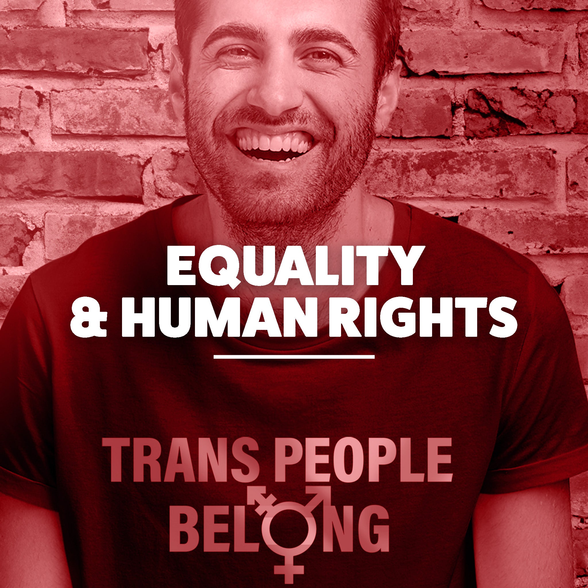 An image of a man with a huge smile. He is wearing a shirt that says “Trans People Belong.” This image is for our Equality and Human Rights Collection. 