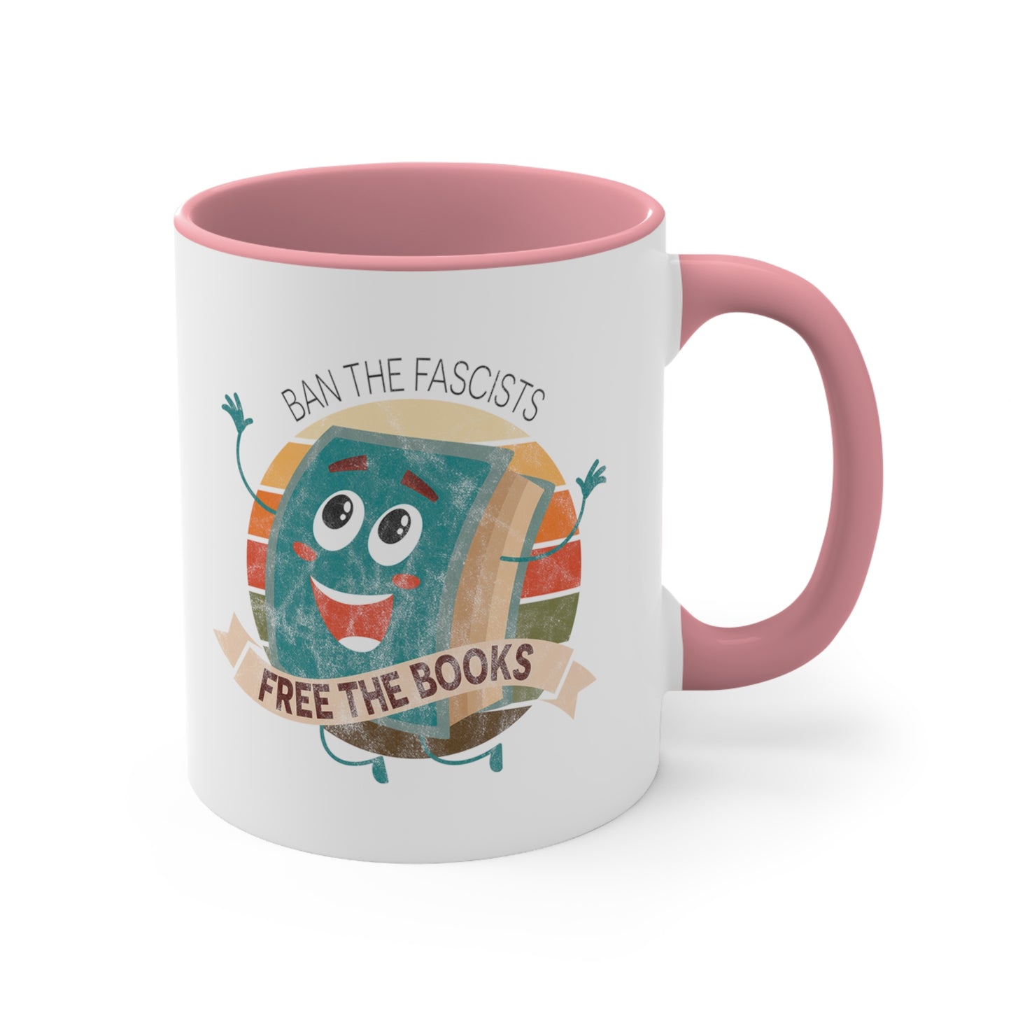 Mug with a pink handle and interior with a graphic that says “Ban the Fascists, Free the Books” with a vintage illustration of a cartoon book leaping for joy. There is a circle of vintage-colored stripes behind it. 