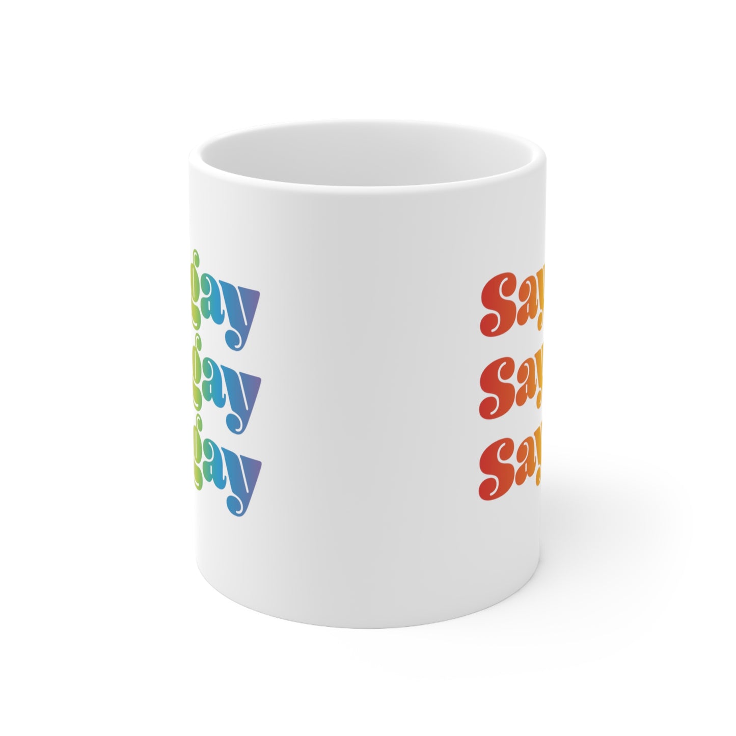 11oz white ceramic mug that reads “Say gay” x3 rows in a thick, rainbow font. This angle only shows the edges of the design.