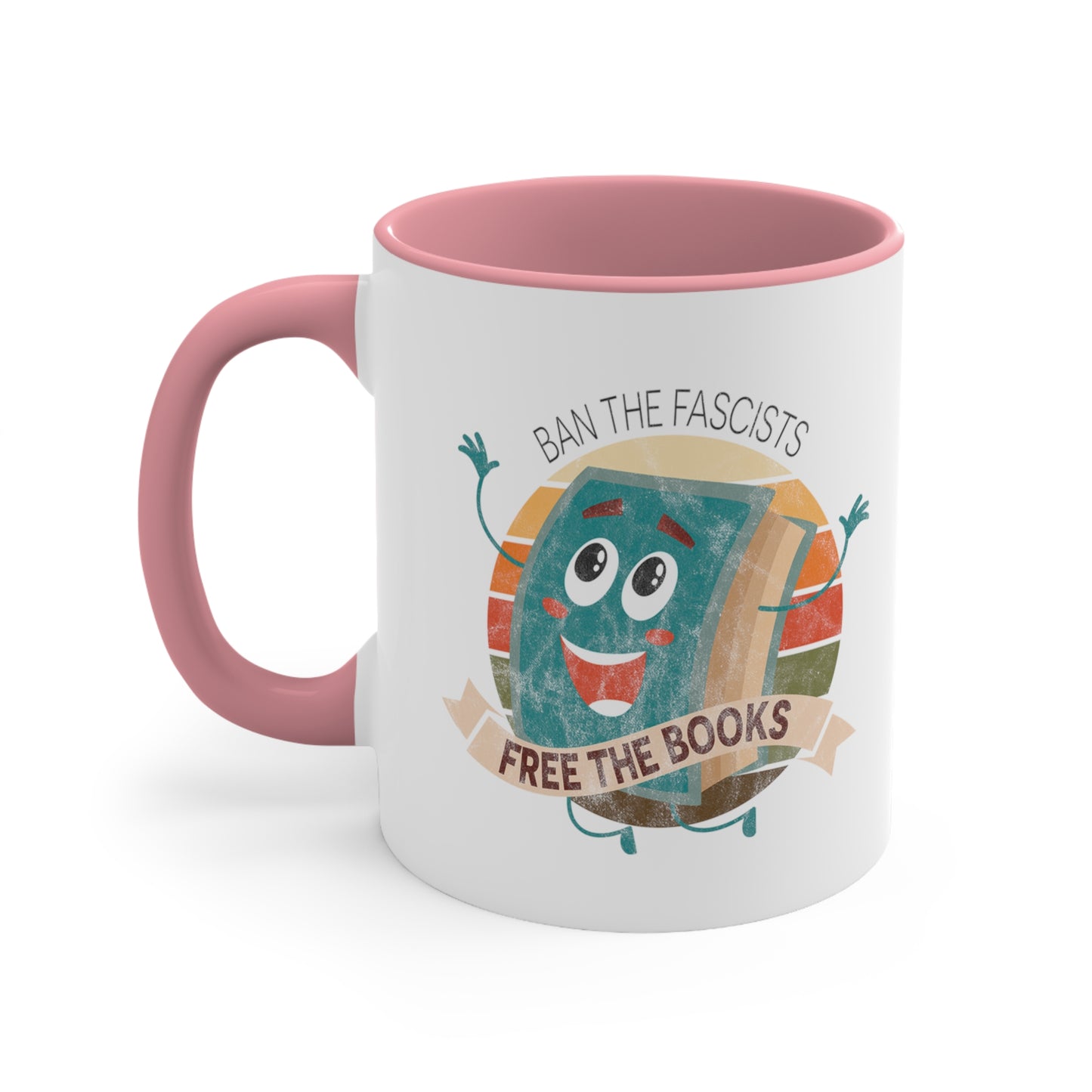 Mug with a pink handle and interior with a graphic that says “Ban the Fascists, Free the Books” with a vintage illustration of a cartoon book leaping for joy. There is a circle of vintage-colored stripes behind it. 