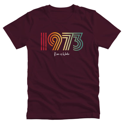 Maroon unisex t-shirt that says, “1973 Roe vs Wade.” The numbers are in a round, lined retro font in a rainbow-gradient color. “Roe vs Wade” is beneath it in a script font.