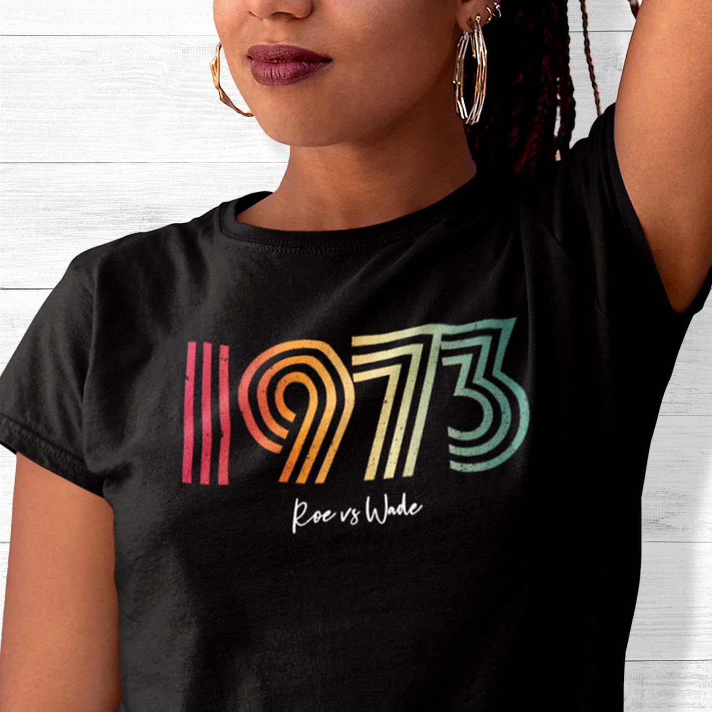 Black unisex t-shirt that says, “1973 Roe vs Wade.” The numbers are in a round, lined retro font in a rainbow-gradient color. “Roe vs Wade” is beneath it in a script font.