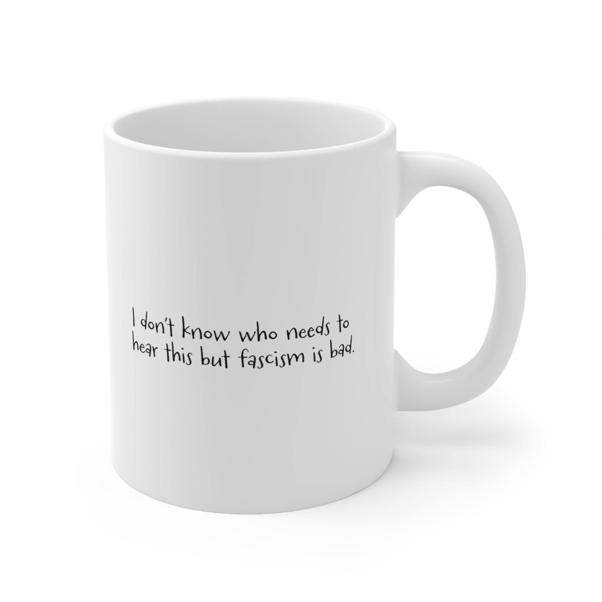 White ceramic mug with the handle facing the right that reads "I don't know who needs to hear this but fascism is bad." The text is written in a handwritten font.