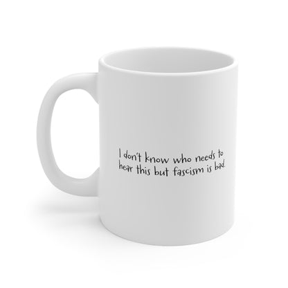 White ceramic mug with the handle facing the left that reads "I don't know who needs to hear this but fascism is bad." The text is written in a handwritten font.