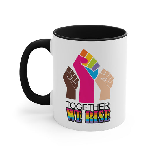 Black accented 11oz ceramic mug ]with a graphic a brown skin-colored fist on the left, a rainbow fist front and center, and a white skin-colored fist on the right. Below that reads “Together We Rise.” “Together” is on one line and “We Rise” is below that in rainbow colors. The inside of the mug and the handle are both black.