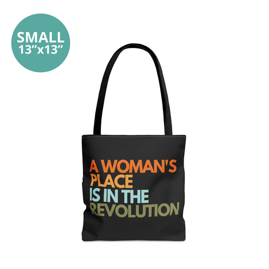 Small-sized 13x13” black canvas tote bag that says, “A woman’s place is in the revolution” in a round, modern font in all caps and left aligned. Each line is a different color. “A Woman’s” is orange, “place” is yellow-orange, “is in the” is light blue, and “revolution” is military green.