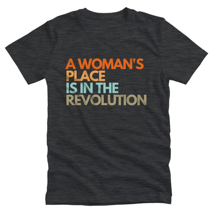 Dark Grey Heather color unisex t-shirt that says “A woman’s place is in the revolution” in a round, modern font in all caps and left aligned. Each line is a different color. “A Woman’s” is orange, “place” is yellow-orange, “is in the” is light blue, and “revolution” is military green.