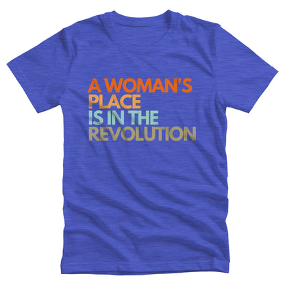 Heather True Royal color unisex t-shirt that says “A woman’s place is in the revolution” in a round, modern font in all caps and left aligned. Each line is a different color. “A Woman’s” is orange, “place” is yellow-orange, “is in the” is light blue, and “revolution” is military green.