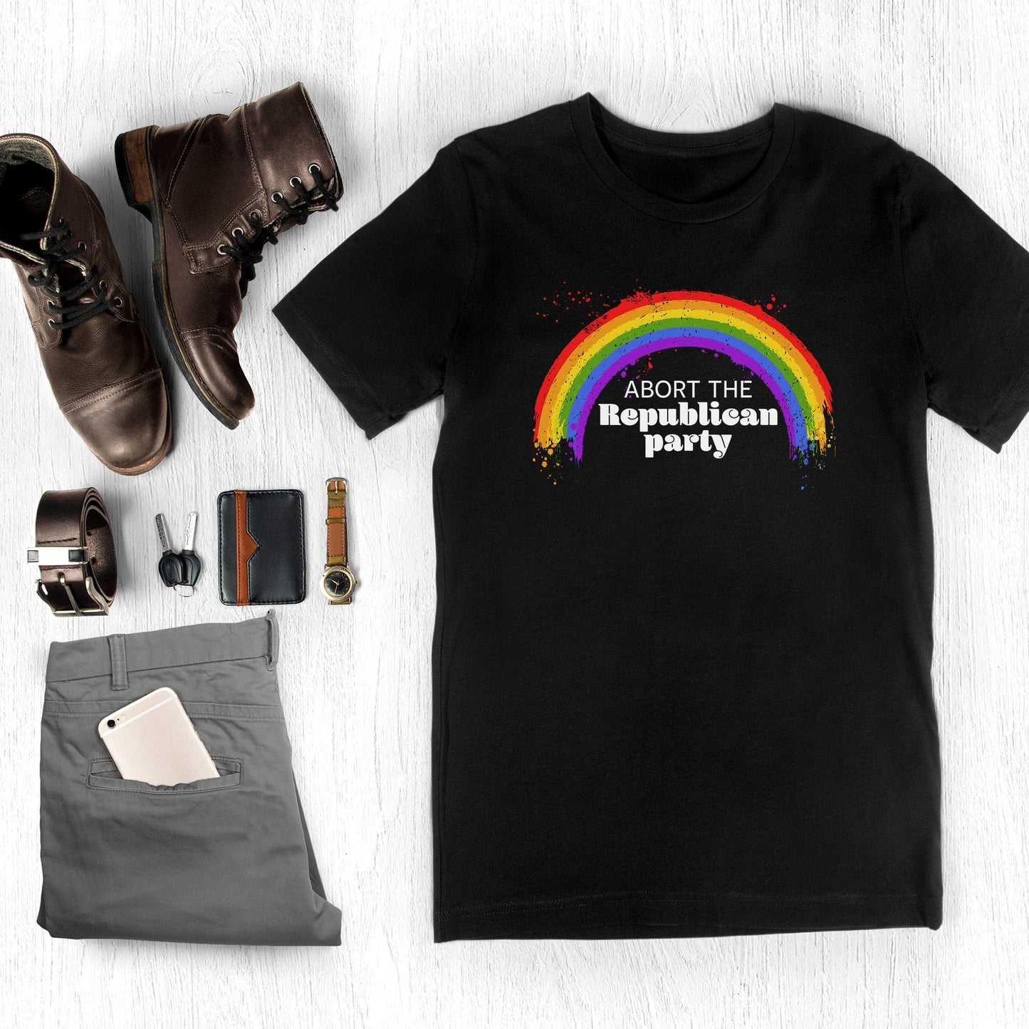 Black unisex t-shirt with a graphic of a rainbow with small paint splatters around it. Inside the negative space of the rainbow is the text, “Abort the Republican Party.” 