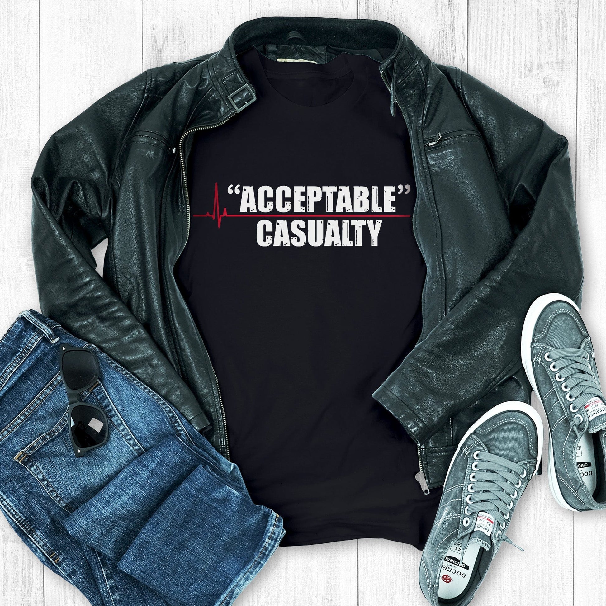 Black unisex t-shirt that says, “Acceptable” Casualty with each word on its own line. There is a red heartbeat graphic to the left of the text with a straight, flat line extending out between the two words.