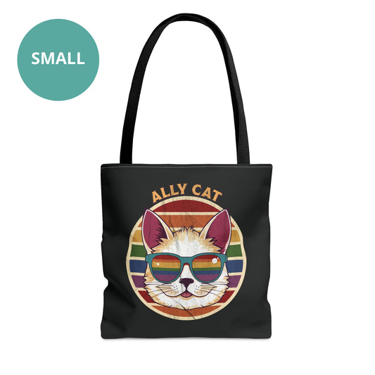 Black tote bag with a black handle with a circular retro-inspired image of a cat wearing rainbow sunglasses with a retro sunset made from parallel lines behind it. The text reads “ALLY CAT” in all caps, arched over the image. The graphic has a retro, worn texture.