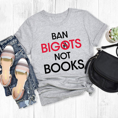 Athletic Heather color unisex t-shirt that says, “Ban Bigots Not Books” in all caps. Each word is on its own line. The word “Bigots” is red and the “O” has a line illustration of a church inside it with a slash to cross it out.