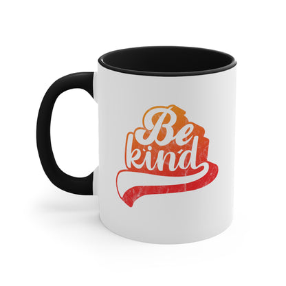 11oz ceramic mug with a black handle and interior that says, “Be Kind” in a script font that is an orange gradient color. The “d” has a unique swoosh glyph extending below the word, adding a dynamic and flowing aesthetic to the text.