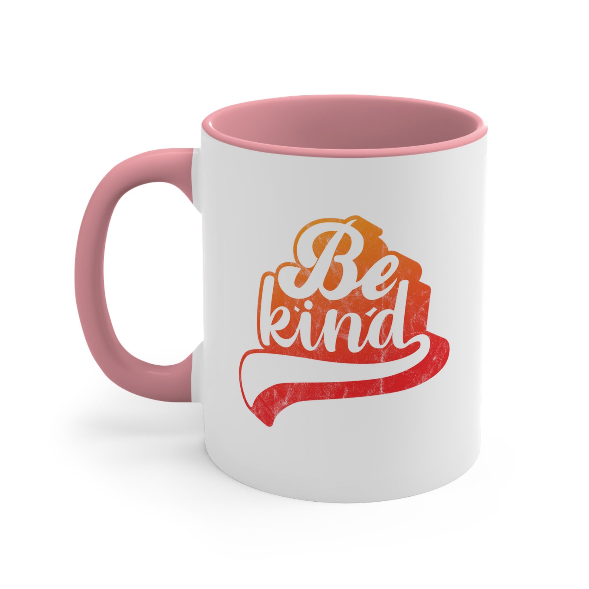 11oz ceramic mug with a pink handle and interior that says, “Be Kind” in a script font that is an orange gradient color. The “d” has a unique swoosh glyph extending below the word, adding a dynamic and flowing aesthetic to the text.