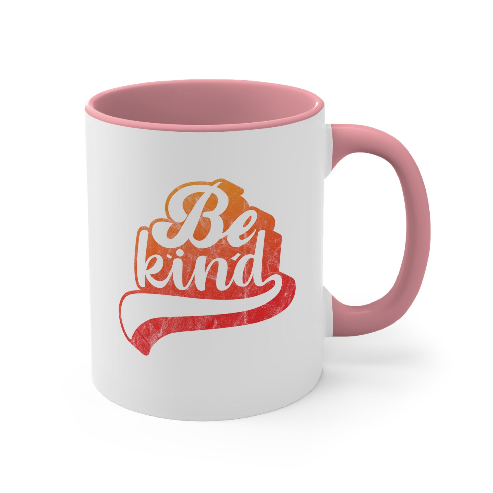 11oz ceramic mug with a pink handle and interior that says, “Be Kind” in a script font that is an orange gradient color. The “d” has a unique swoosh glyph extending below the word, adding a dynamic and flowing aesthetic to the text.