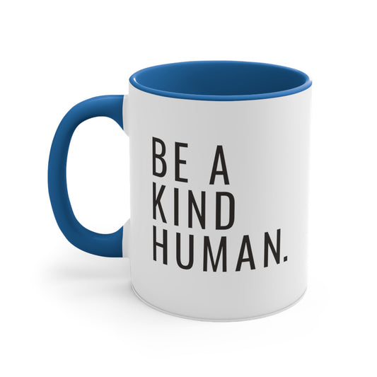 11oz ceramic mug with a blue handle and interior featuring the phrase 'Be a kind human.' in all caps, left-justified, with a clean, narrow, sans-serif font.