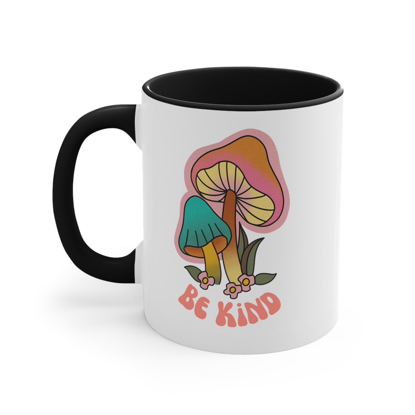 11oz ceramic mug with a black handle and interior that says “Be Kind” on the front in a retro font with two retro mushrooms above the text. The text is slightly arched down.