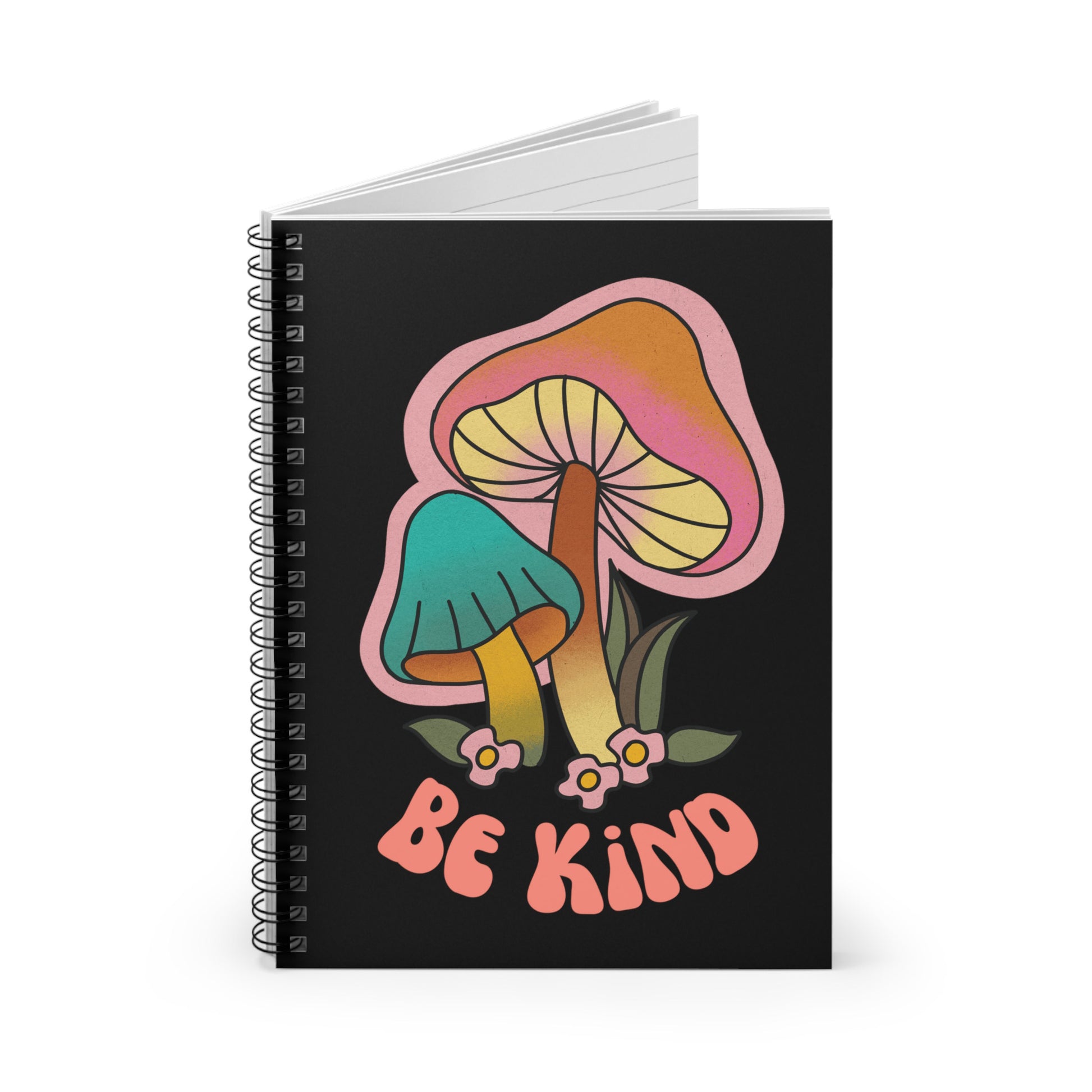 Black spiral notebook that says “Be Kind” on the front in a retro font with two retro mushrooms above the text. The text is slightly arched down.