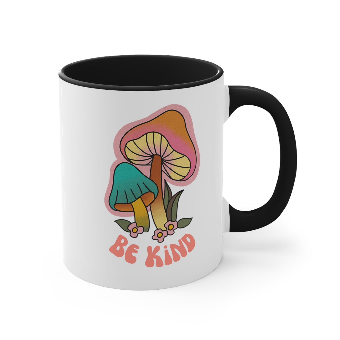 11oz ceramic mug with a black handle and interior that says “Be Kind” on the front in a retro font with two retro mushrooms above the text. The text is slightly arched down.