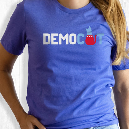 Heather True Royal color unisex t-shirt that says “DEMOCAT.” The “A” is an illustration of a cat that’s blue at the top and red at the bottom.