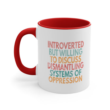 11oz ceramic mug with a red interior and handle with a graphic that says “Introverted but willing to discuss dismantling systems of oppression.” The graphic is slightly distressed, and each line of the graphic is a different color.