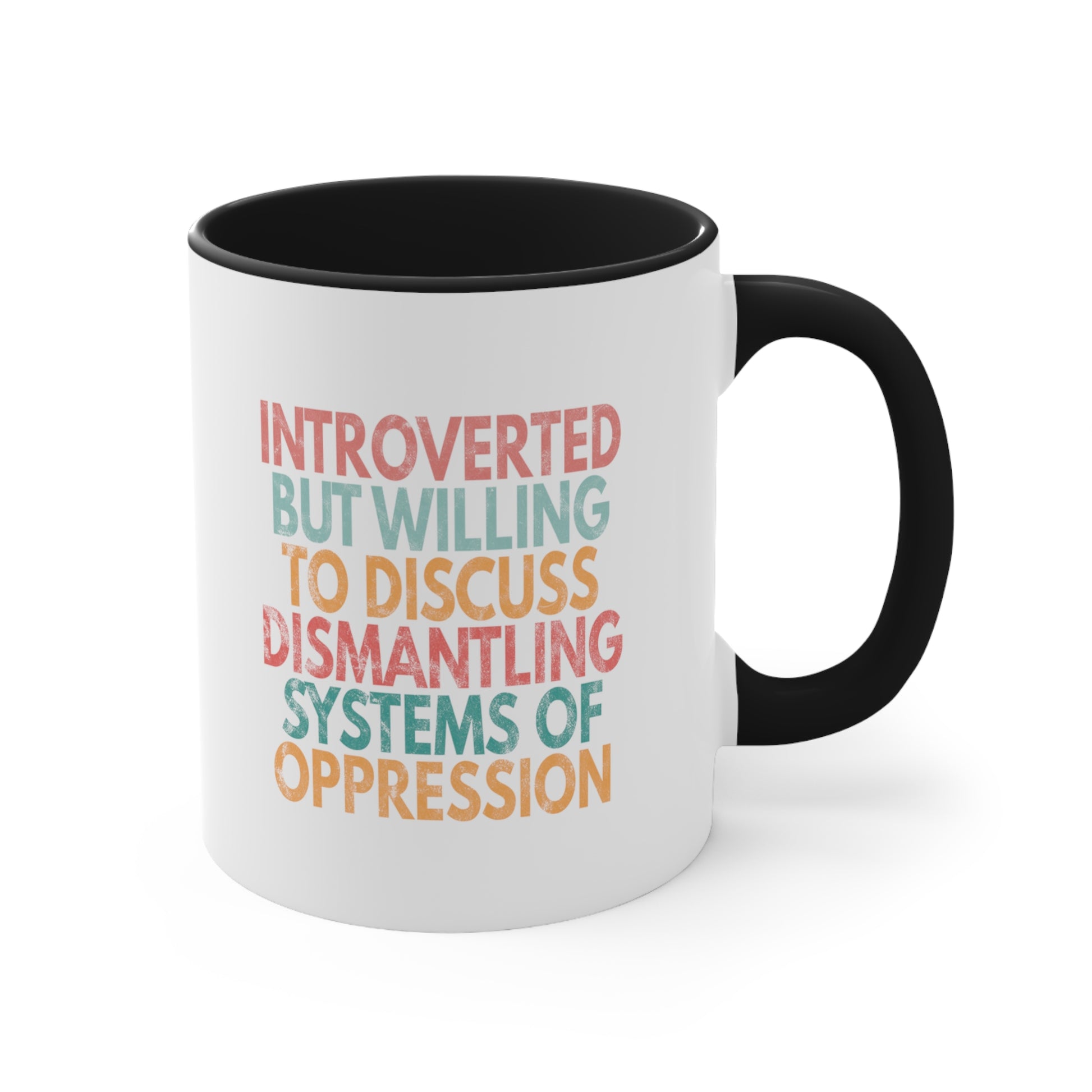 11oz ceramic mug with a black interior and handle with a graphic that says “Introverted but willing to discuss dismantling systems of oppression.” The graphic is slightly distressed, and each line of the graphic is a different color.