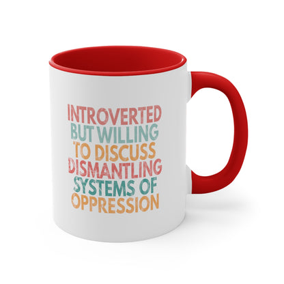 11oz ceramic mug with a red interior and handle with a graphic that says “Introverted but willing to discuss dismantling systems of oppression.” The graphic is slightly distressed, and each line of the graphic is a different color.