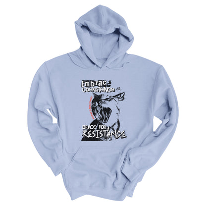 Light Blue color hoodie featuring the phrase 'Embrace Coexistence or Brace for Resistance' in a grunge font. The shirt includes an illustration of a cat meowing loudly with a small crown to the right, adding to the grunge aesthetic. Small red letters along the left side of the cat's face, written vertically say, ‘Kindness is revolutionary' in all caps.