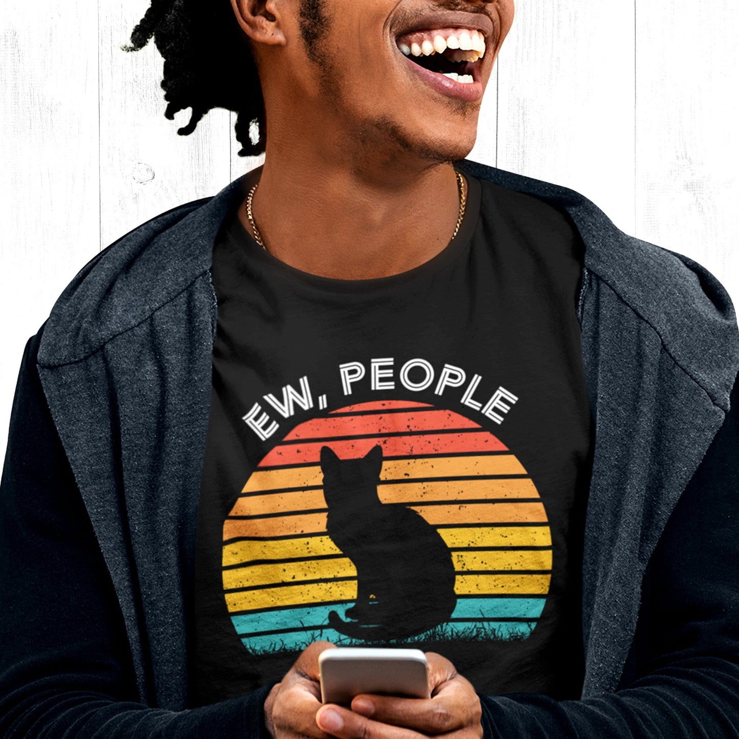 Black unisex t-shirt that says, “Ew People” in all caps. The text is arched over a circular image of a sunset that’s made up of horizontal lines. There is a silhouette of a black cat over the graphic.