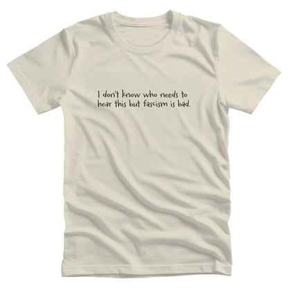 Natural color unisex t-shirt that reads in a hand-written font, “I don’t know who needs to hear this but fascism is bad.” It takes up two lines.