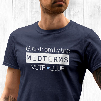 Navy Blue unisex t-shirt that say, “Grab them by the midterms. Vote Blue.” The word “Midterms” is in a white rectangle.