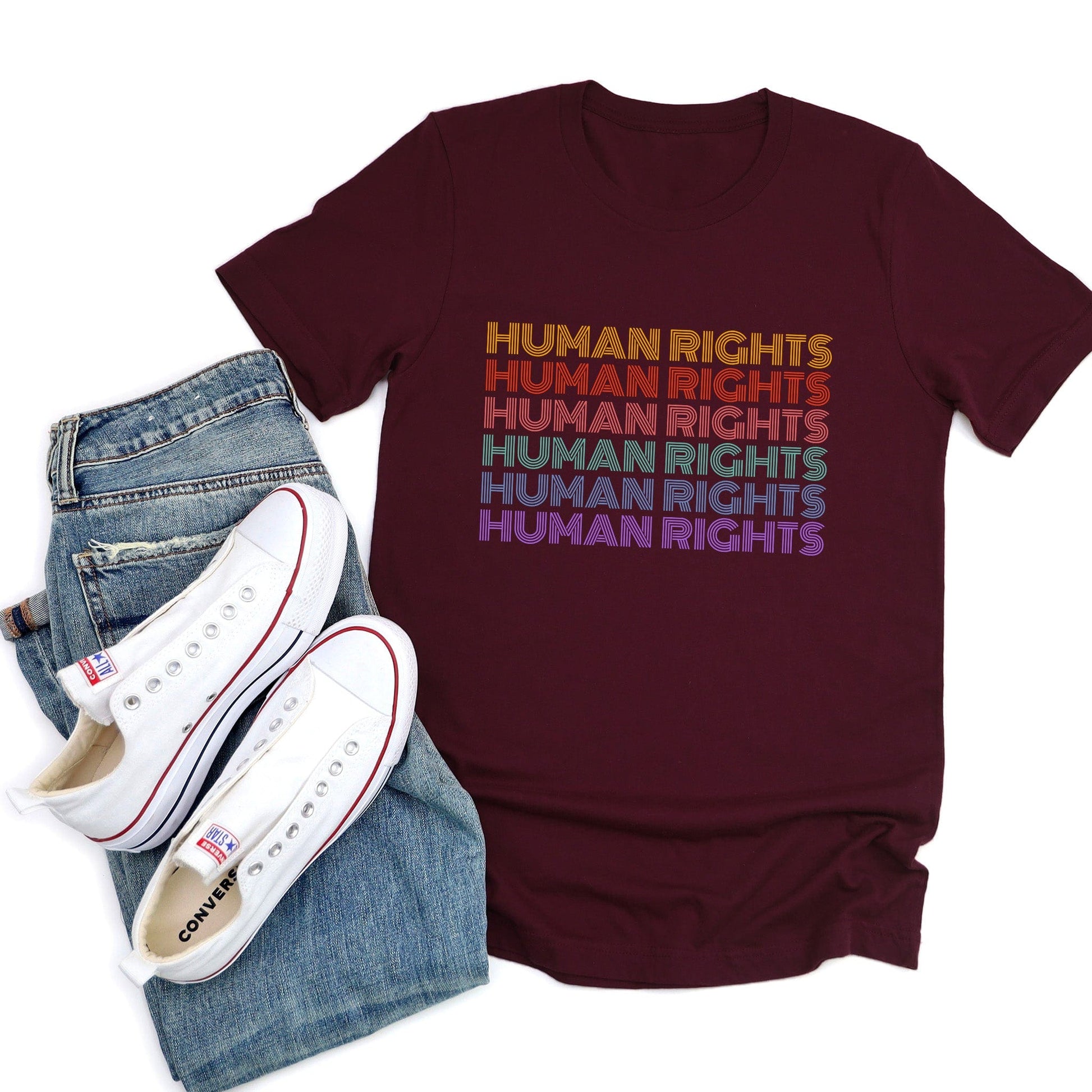 Maroon unisex t-shirt that says, “HUMAN RIGHTS” six times. The first row is yellow, the second row is burgundy/red, the third row is dark pink, the fourth row is teal, the fifth row is dark blue, and the last row is purple.