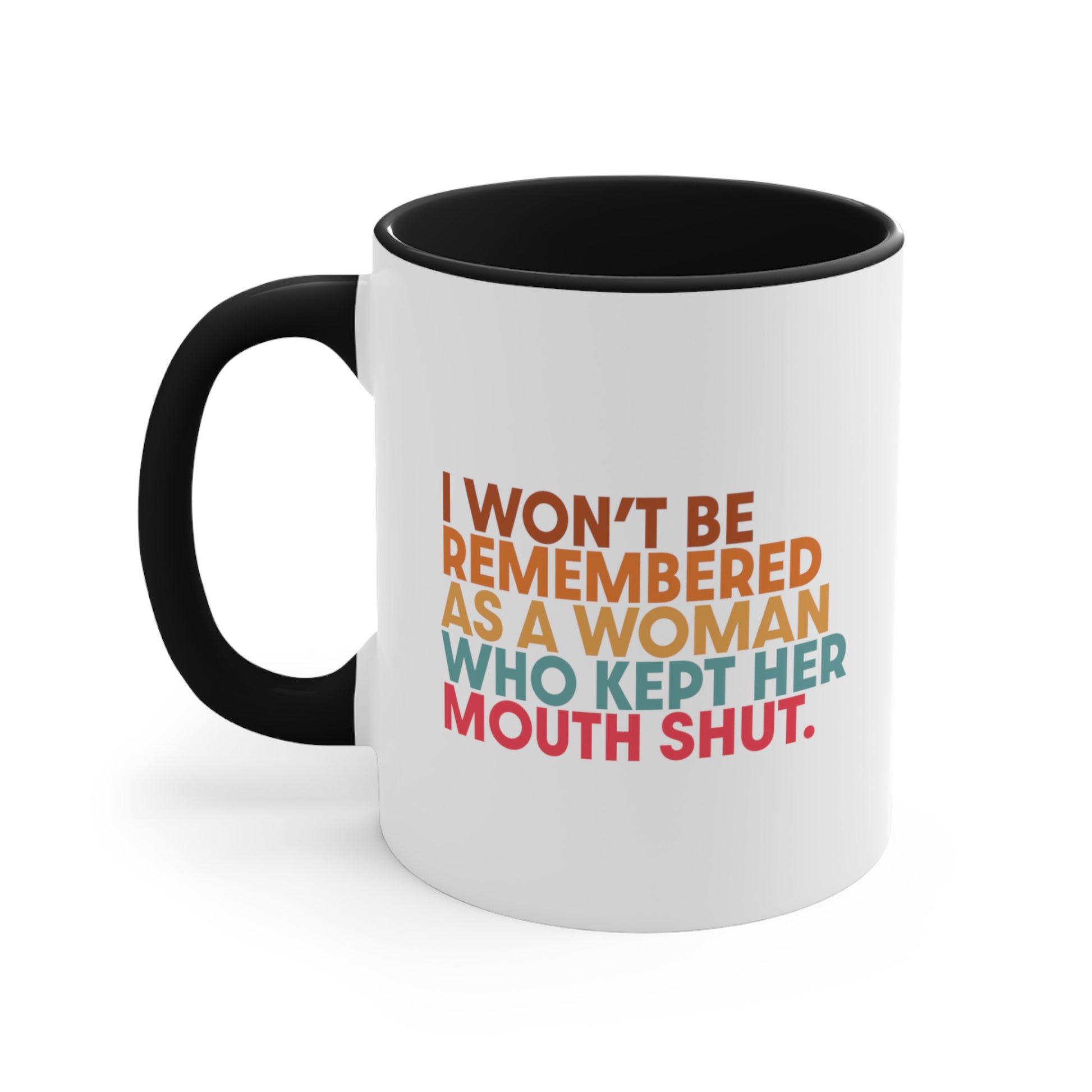 11oz ceramic mug with a black handle and interior that says, “I won’t be remembered as a woman who kept her mouth shut” in all caps. The phrase is on 5 lines, with each line being a different color. “I won’t be” is brown, “remembered” is orange, “as a woman” is yellow-orange, “who kept her” is blue-green, and “mouth shut” is pink-red. 