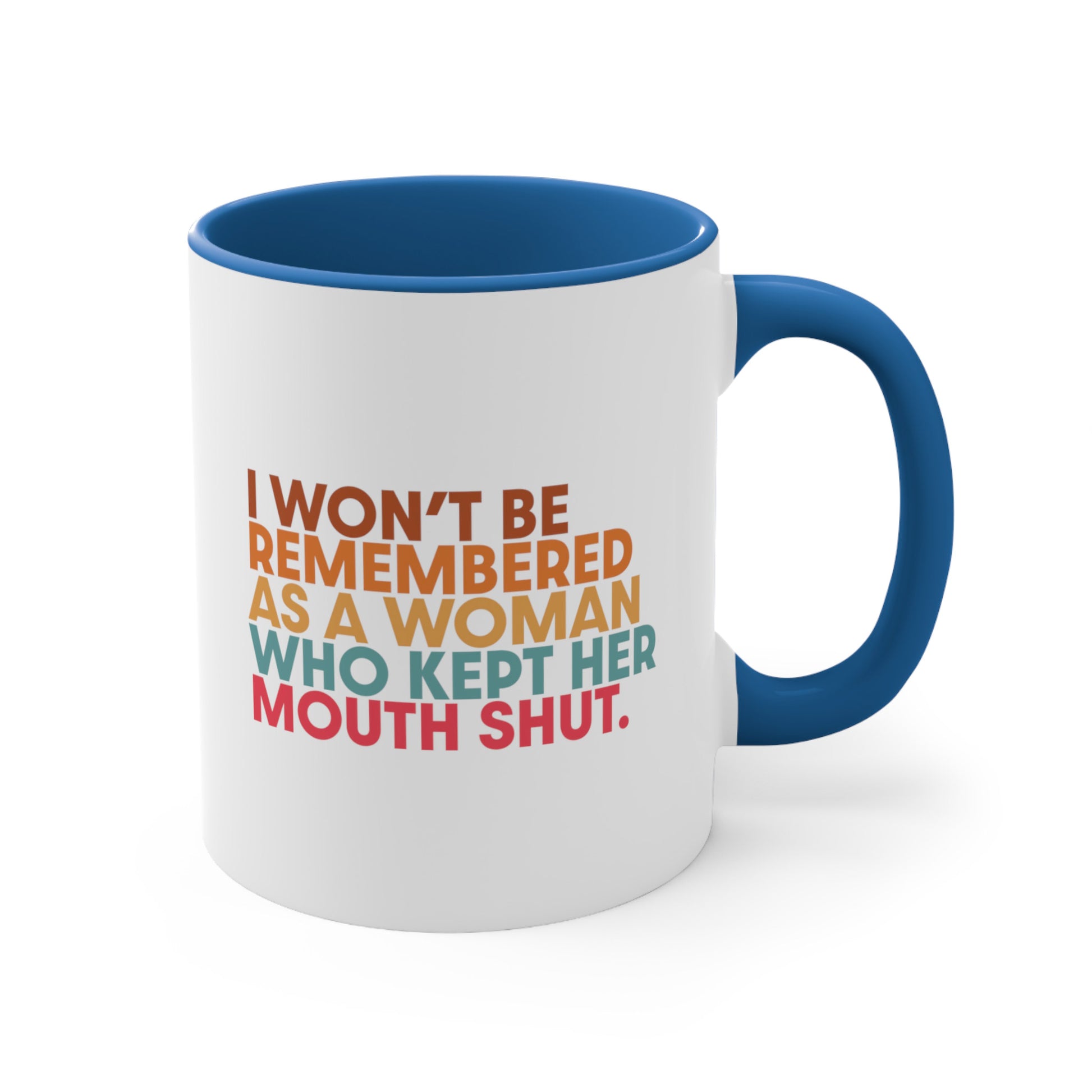 11oz ceramic mug with a blue handle and interior that says, “I won’t be remembered as a woman who kept her mouth shut” in all caps. The phrase is on 5 lines, with each line being a different color. “I won’t be” is brown, “remembered” is orange, “as a woman” is yellow-orange, “who kept her” is blue-green, and “mouth shut” is pink-red. 