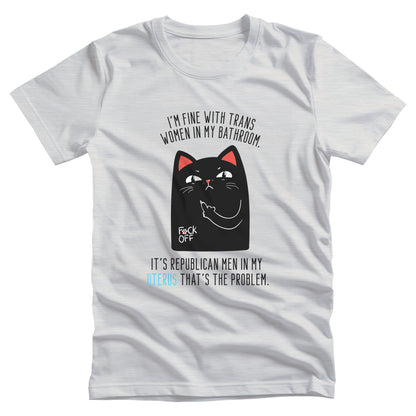 Ash color unisex t-shirt with a graphic of an annoyed cat showing its middle finger. The text says “I’m fine with trans women in my bathroom” above the graphic, slightly arched. Below the graphic reads “It’s Republican men in my uterus that’s the problem.”