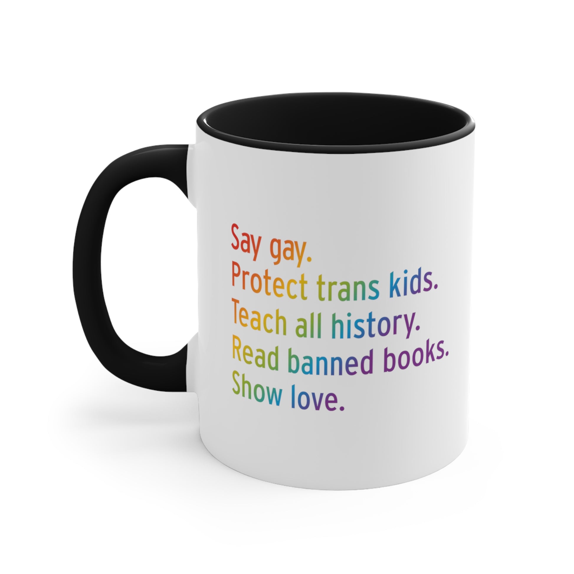 11oz white ceramic mug colored black on the inside of the mug and the handle. The text says “Say gay. Protect Trans Kids. Teach all history. Read banned books. Show love.” Each sentence is on its own line, and the entire graphic is colored with a rainbow gradient.