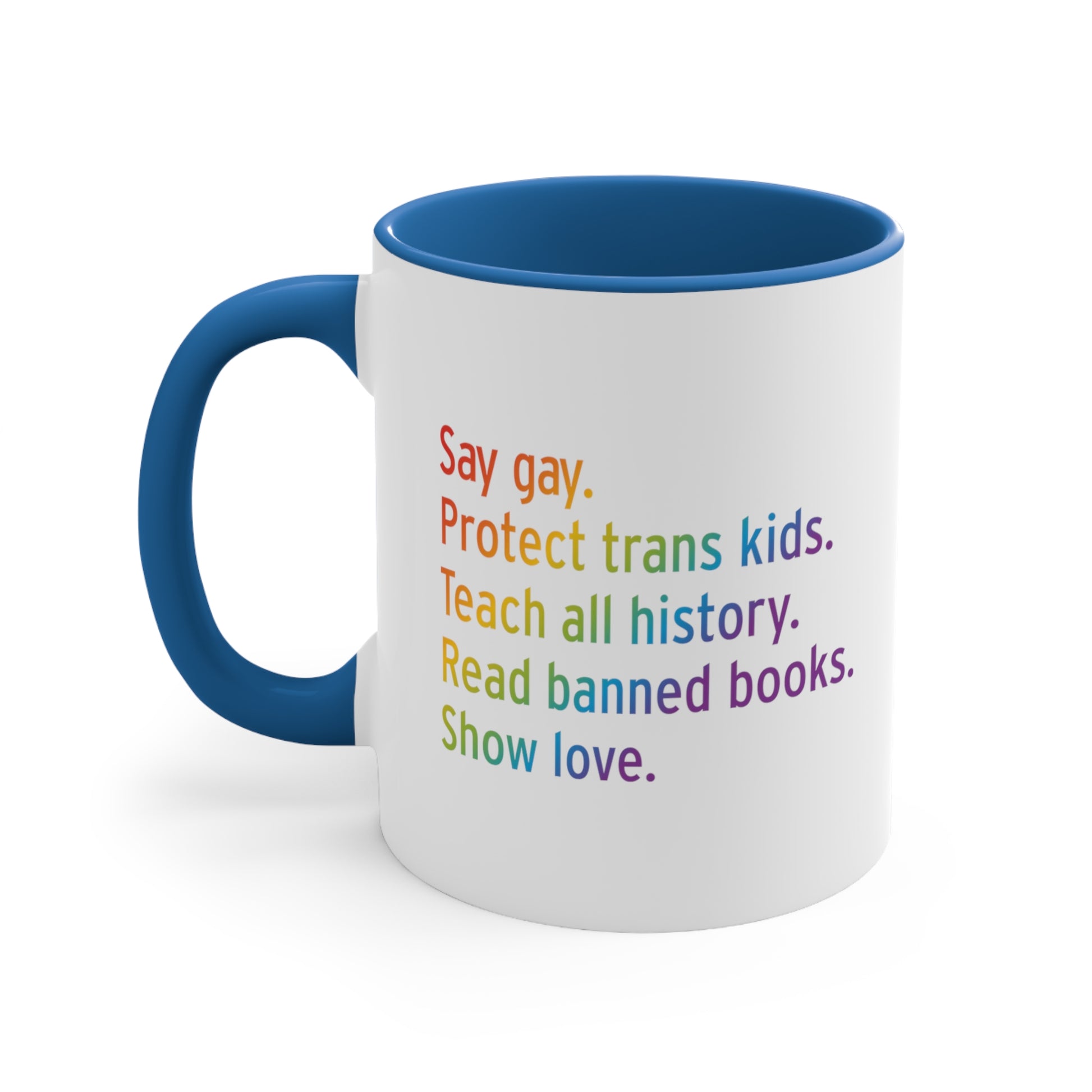 11oz white ceramic mug colored blue on the inside of the mug and the handle. The text says “Say gay. Protect Trans Kids. Teach all history. Read banned books. Show love.” Each sentence is on its own line, and the entire graphic is colored with a rainbow gradient.