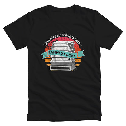 Black color unisex t-shirt with a graphic that says, “Introverted but willing to discuss banned books.” The image has stacked books with a circular retro sunset behind it. “Introverted but willing to discuss” is arched over the graphic, and “banned books” is inside a wavey blue-green colored ribbon.