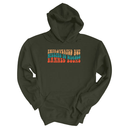 Military Green color unisex hoodie with a graphic that says “Introverted but willing to discuss banned books” in a retro, 1970s bubble font. Each line is a different color. The graphic is slightly distressed.