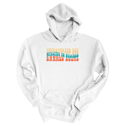 White unisex hoodie with a graphic that says “Introverted but willing to discuss banned books” in a retro, 1970s bubble font. Each line is a different color. The graphic is slightly distressed.