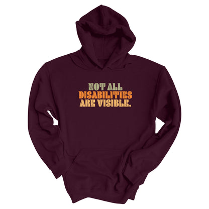 Maroon hoodie that says, “Not all disabilities are visible” in a thick, retro font in all caps. Each line is a different color. “Not all” is light green, “disabilities” is orange, and “are visible” is yellow. The graphic has a retro look and is slightly distressed.