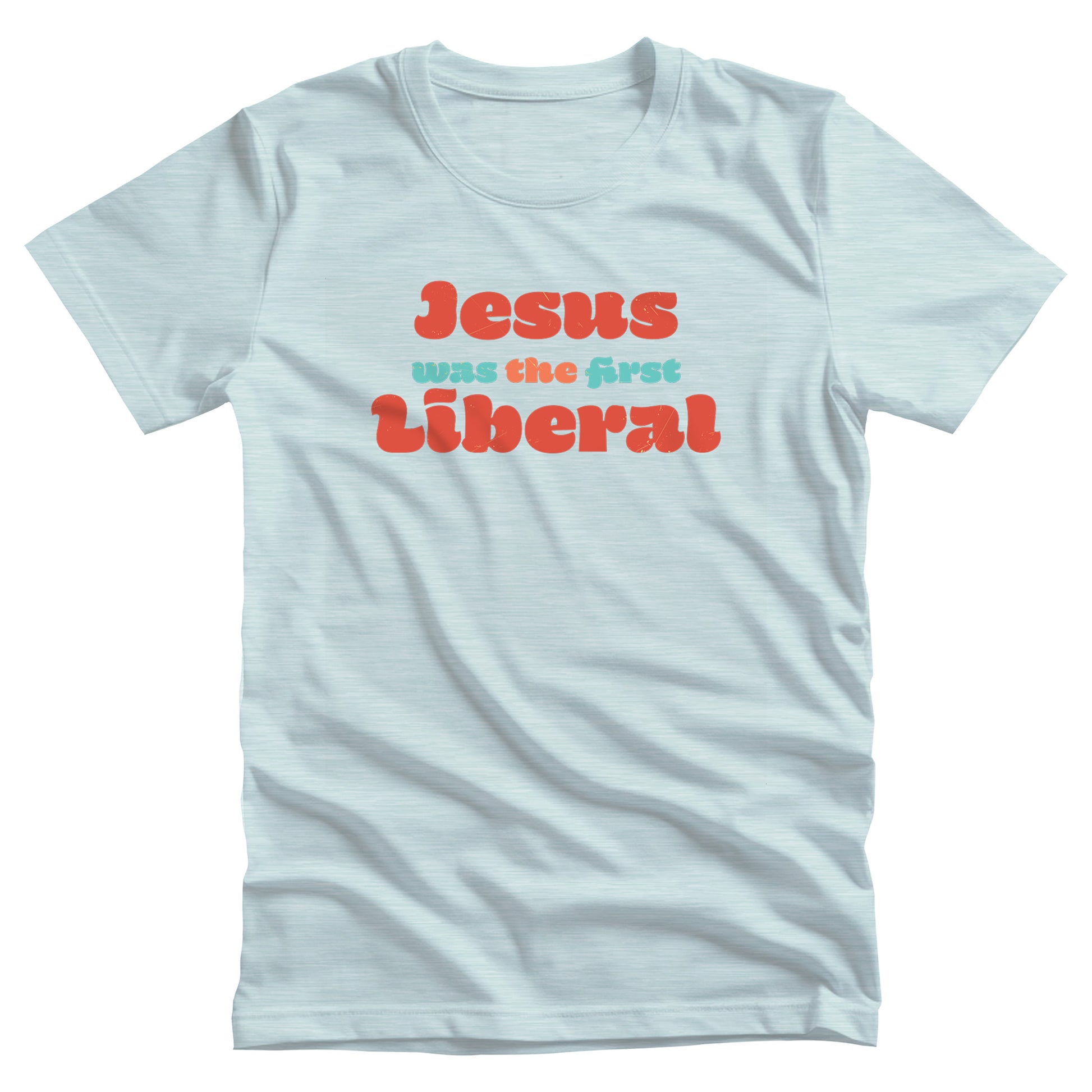 Heather Ice Blue color unisex t-shirt that says, “Jesus was the first Liberal.” The words “Jesus”, “the”, and “Liberal” are all a shade of orange, and the words “Was” and “First” are a light blue-green.