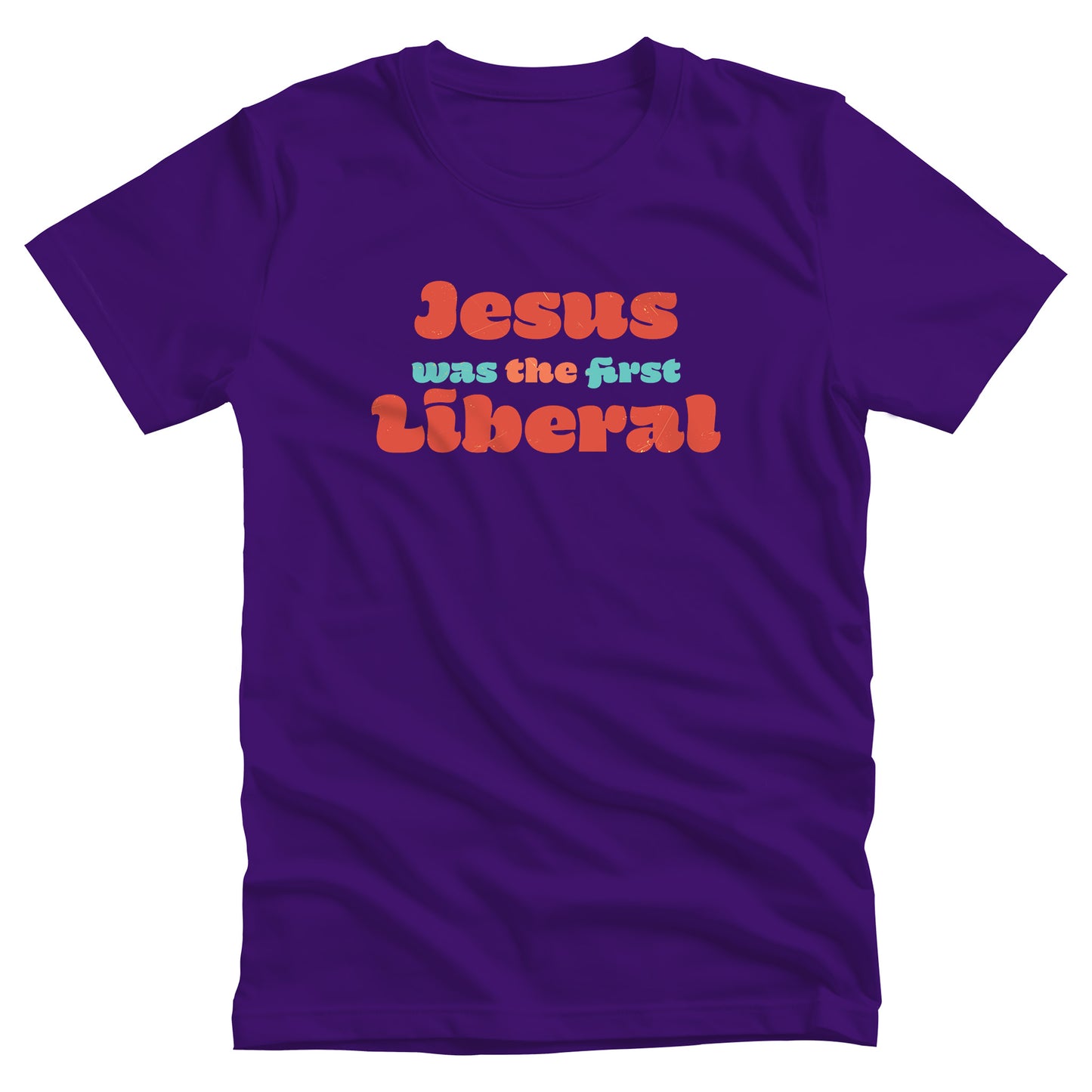 Team Purple color unisex t-shirt that says, “Jesus was the first Liberal.” The words “Jesus”, “the”, and “Liberal” are all a shade of orange, and the words “Was” and “First” are a light blue-green.