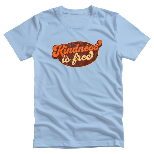 Baby Blue color unisex t-shirt with a retro graphic that says “Kindness is free.” The text is in a script font with a brown oval behind it. The “k” and the “s” in the word “Kindness” are not contained inside the oval. The graphic is also distressed to add to the retro feel.