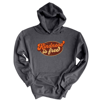 Dark Heather color unisex hoodie with a retro graphic that says “Kindness is free.” The text is in a script font with a brown oval behind it. The “k” and the “s” in the word “Kindness” are not contained inside the oval. The graphic is also distressed to add to the retro feel.