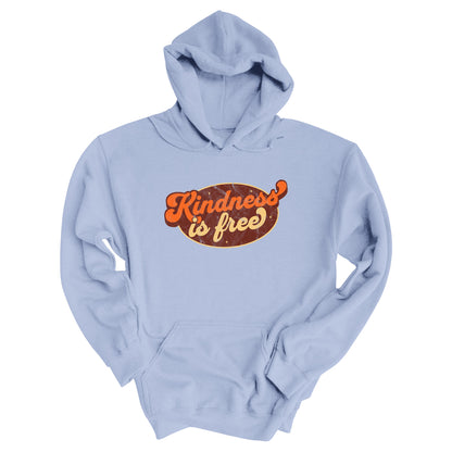Light Blue unisex hoodie with a retro graphic that says “Kindness is free.” The text is in a script font with a brown oval behind it. The “k” and the “s” in the word “Kindness” are not contained inside the oval. The graphic is also distressed to add to the retro feel.