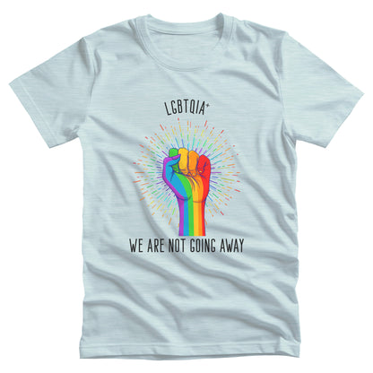 Heather Ice Blue color unisex t-shirt that says, “LGBTQIA+ We Are Not Going Away” with a graphic of a rainbow fist with a rainbow-gradient color starburst behind it. Slightly arched over the starburst are the words “LGBTQIA+” and the rest of the text is below the graphic in one horizontal line.